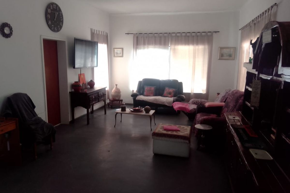 A spacious living room featuring large windows with curtain tracks, providing natural light and a functional layout for comfortable family living.