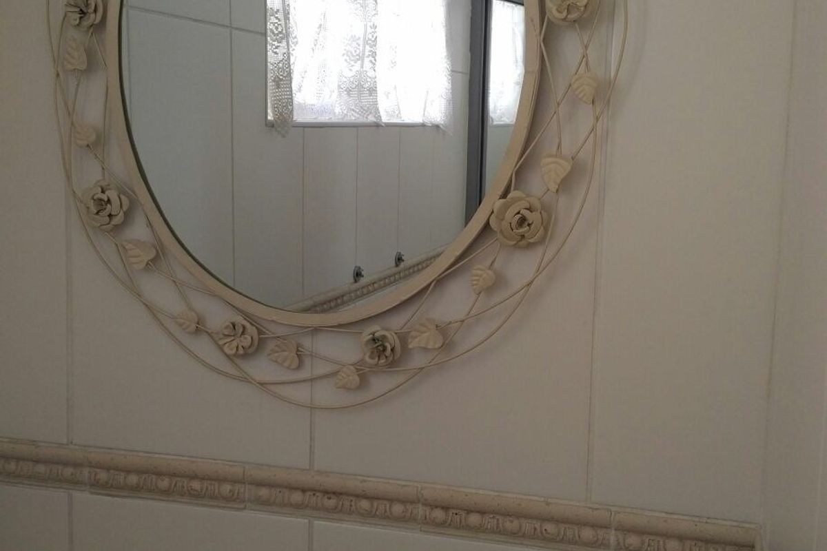 A bathroom featuring white wall tiles with a decorative border and a wall-mounted mirror.