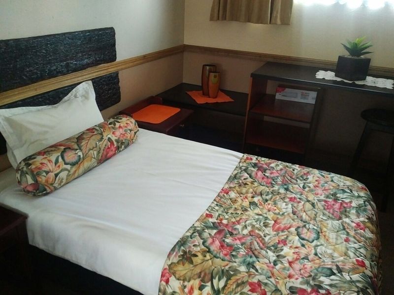 A compact bedroom featuring a wooden headboard and matching dado rail, providing a functional sleeping space.