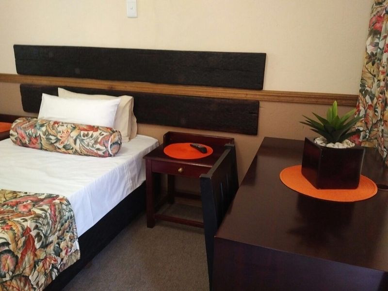 A bedroom featuring timber wall paneling and carpeted flooring, providing a functional sleeping space.