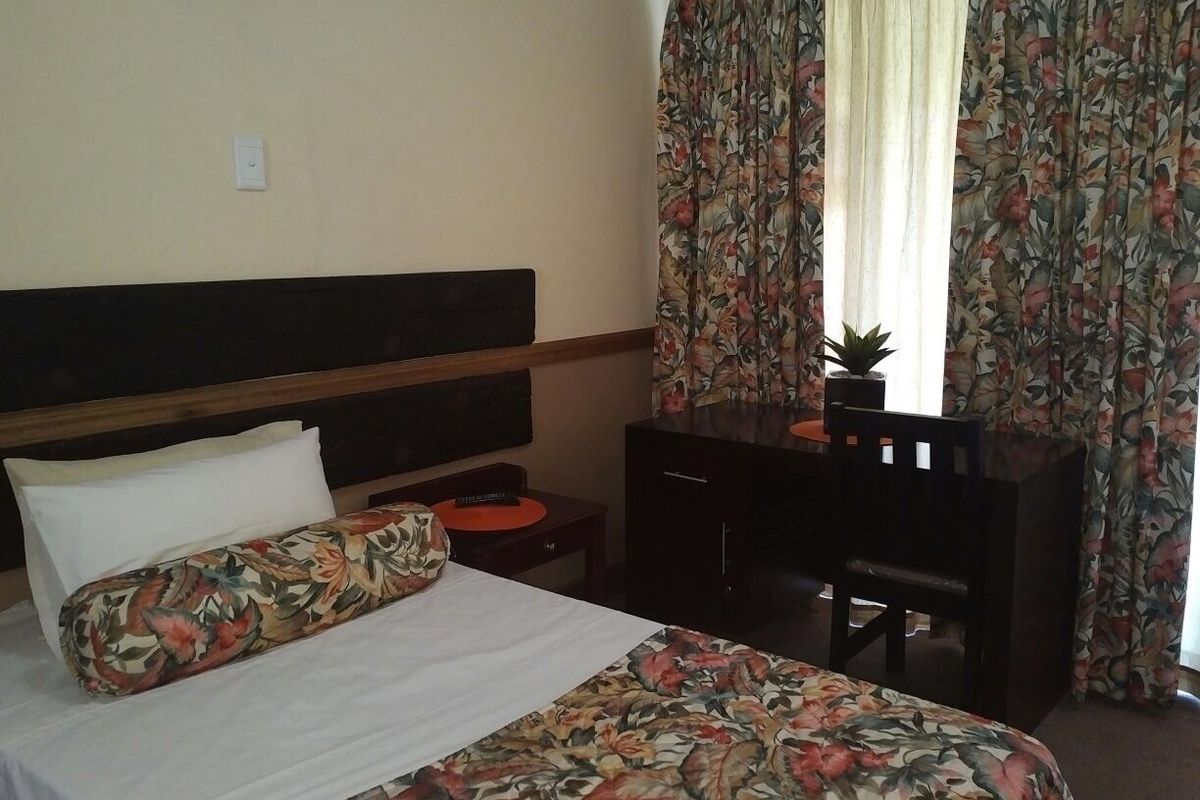 A bedroom featuring a built-in headboard and window with curtains.