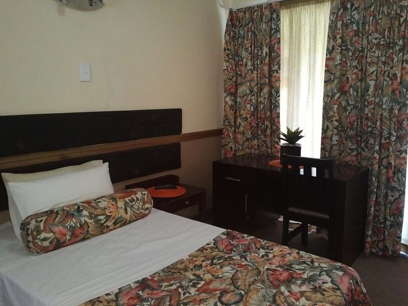 A bedroom featuring a built-in headboard and window with curtains.