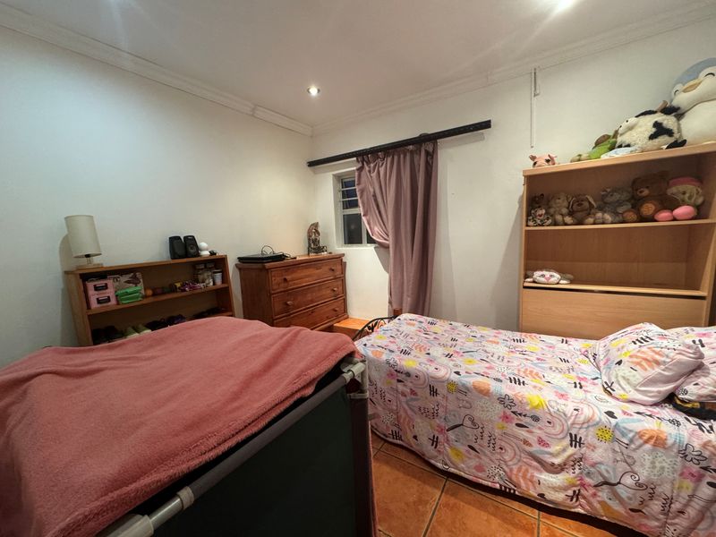 A bedroom featuring tiled flooring, recessed ceiling lighting, and decorative coving, providing a functional space with neutral wall finishes.