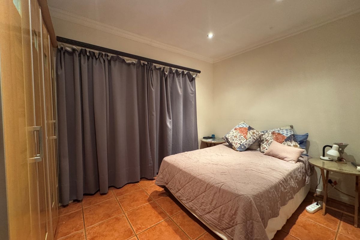 A bedroom featuring tiled flooring, recessed downlighting, and a built-in wardrobe.