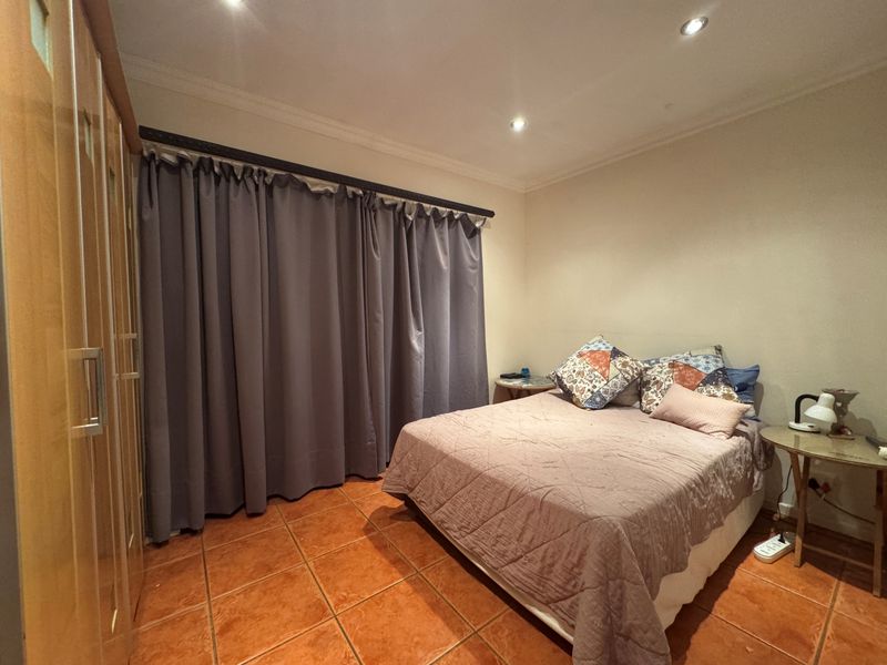 A bedroom featuring tiled flooring, recessed downlighting, and a built-in wardrobe.