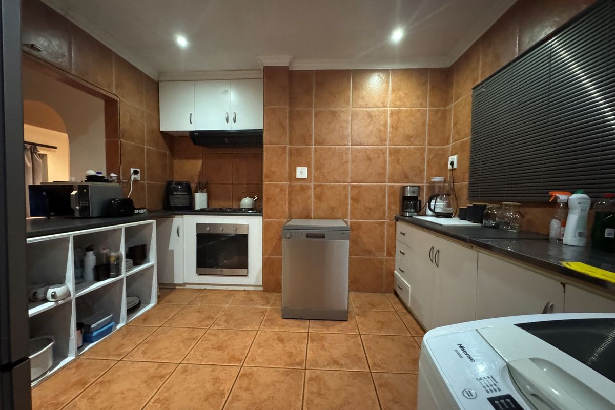 A functional kitchen featuring built-in cabinetry, oven, hob, extractor fan, and tiled finishes throughout, offering a practical layout for daily use.
