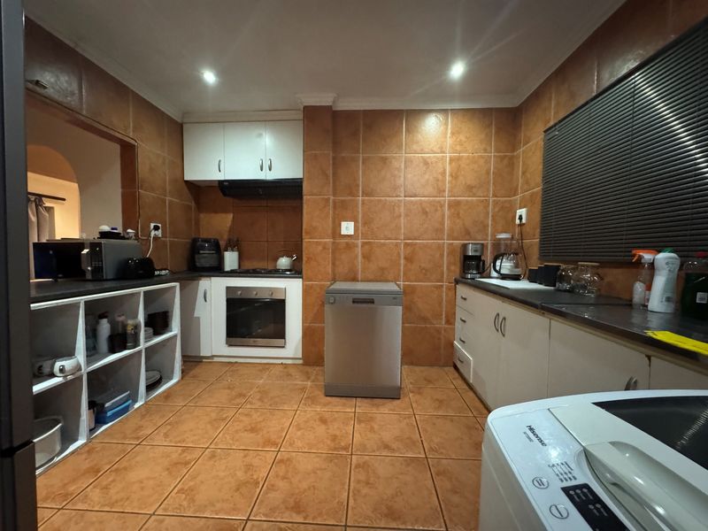A functional kitchen featuring built-in cabinetry, oven, hob, extractor fan, and tiled finishes throughout, offering a practical layout for daily use.