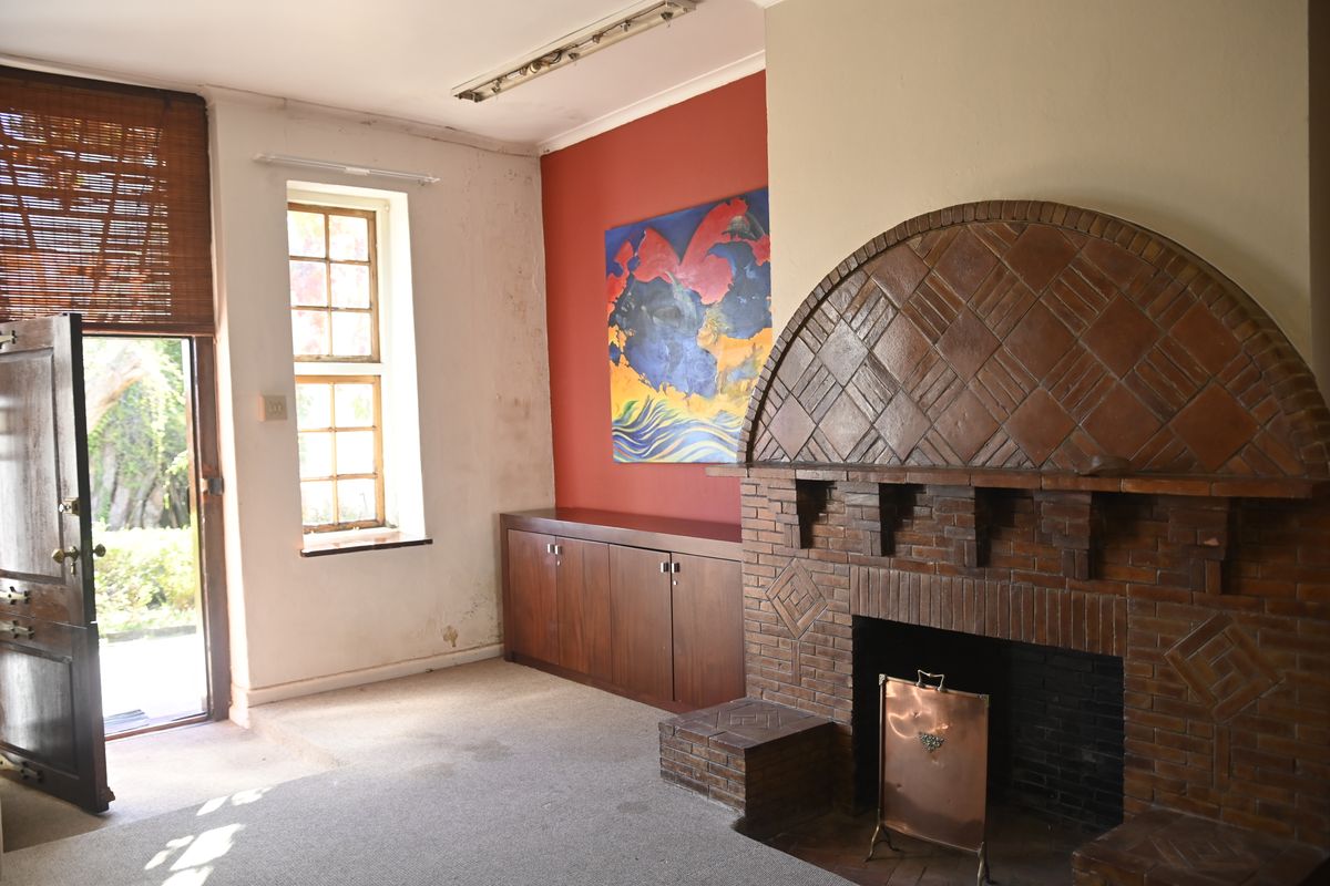 Living room featuring a prominent brick fireplace, built-in wooden cabinetry, and direct access to the garden through a timber door.