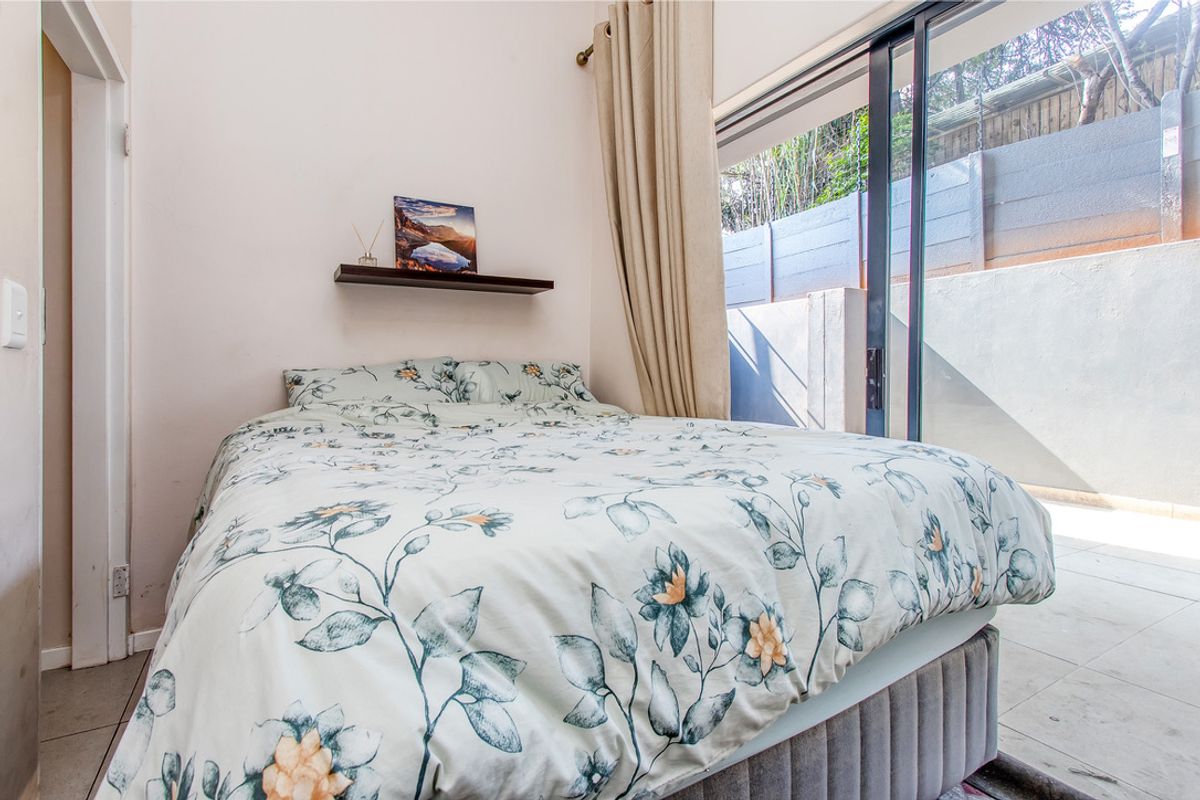 A bright bedroom featuring large sliding glass doors that provide direct access to an outdoor patio area.
