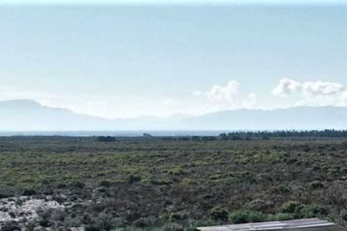 A scenic landscape view overlooking natural vegetation and distant mountain ranges, capturing the expansive rural character of the small holding.