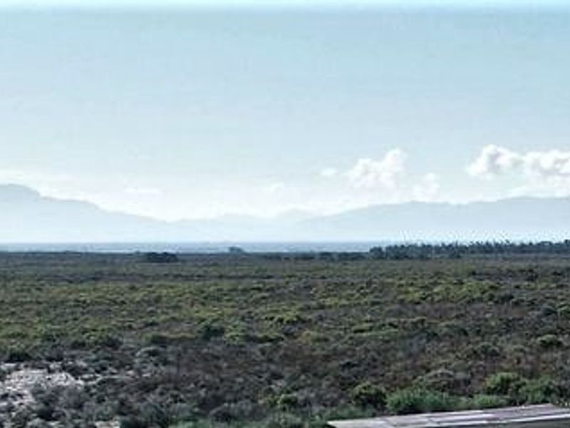 A scenic landscape view overlooking natural vegetation and distant mountain ranges, capturing the expansive rural character of the small holding.