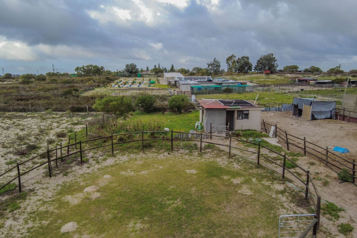 Aerial view of a small holding property featuring a fenced paddock area, a small outbuilding with solar panels, and expansive surrounding agricultural land.