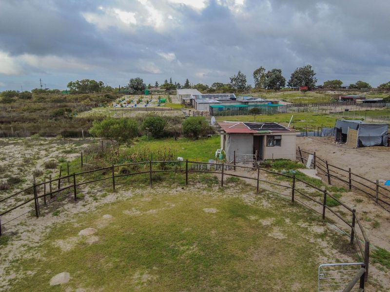 Aerial view of a small holding property featuring a fenced paddock area, a small outbuilding with solar panels, and expansive surrounding agricultural land.