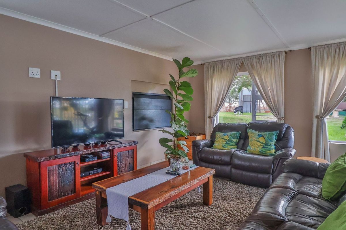A comfortable living room featuring a built-in fireplace, tiled flooring, and large windows providing natural light and garden views.