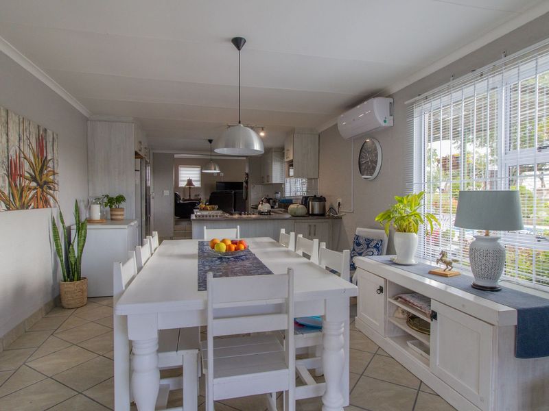 An open-plan dining and kitchen area featuring tiled floors, neutral walls, and modern lighting, creating a bright and functional living space.