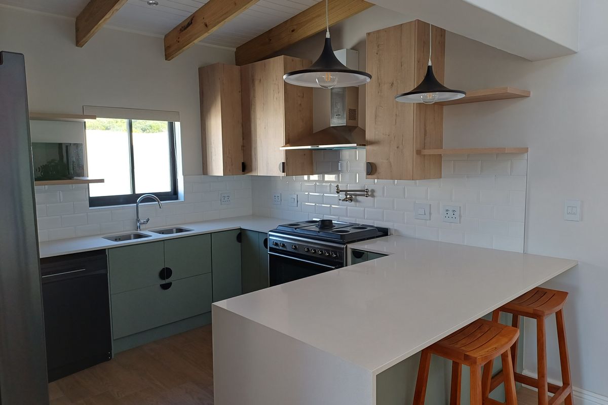 Modern kitchen featuring quartz countertops, subway tile backsplash, gas stove, extractor fan, and exposed timber ceiling beams with a functional breakfast bar.