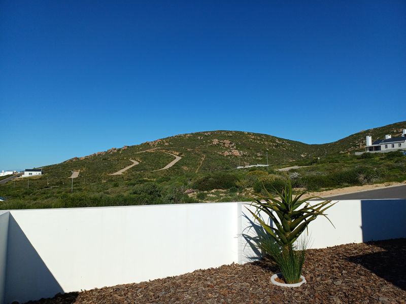 A scenic view of the surrounding hilly landscape and natural terrain, captured from the property's boundary wall.