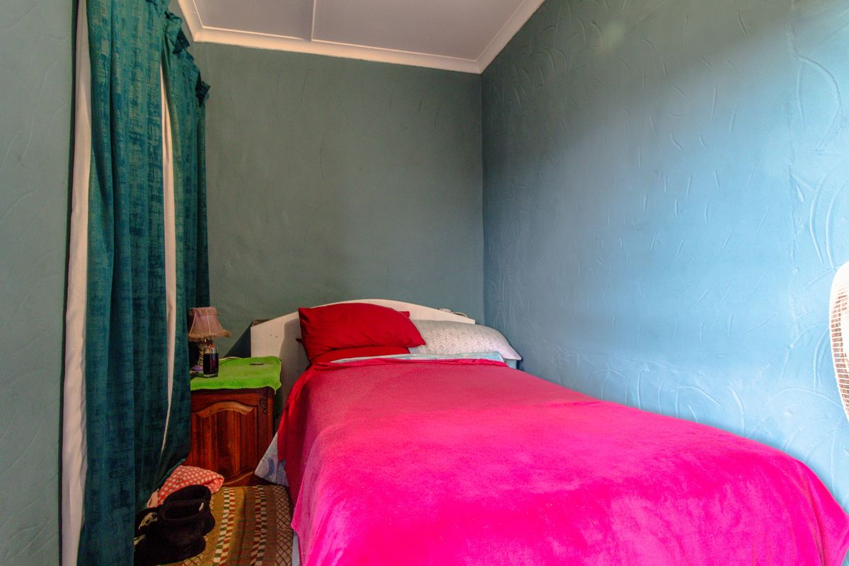 A compact bedroom featuring textured blue walls and a window with floor-length curtains.