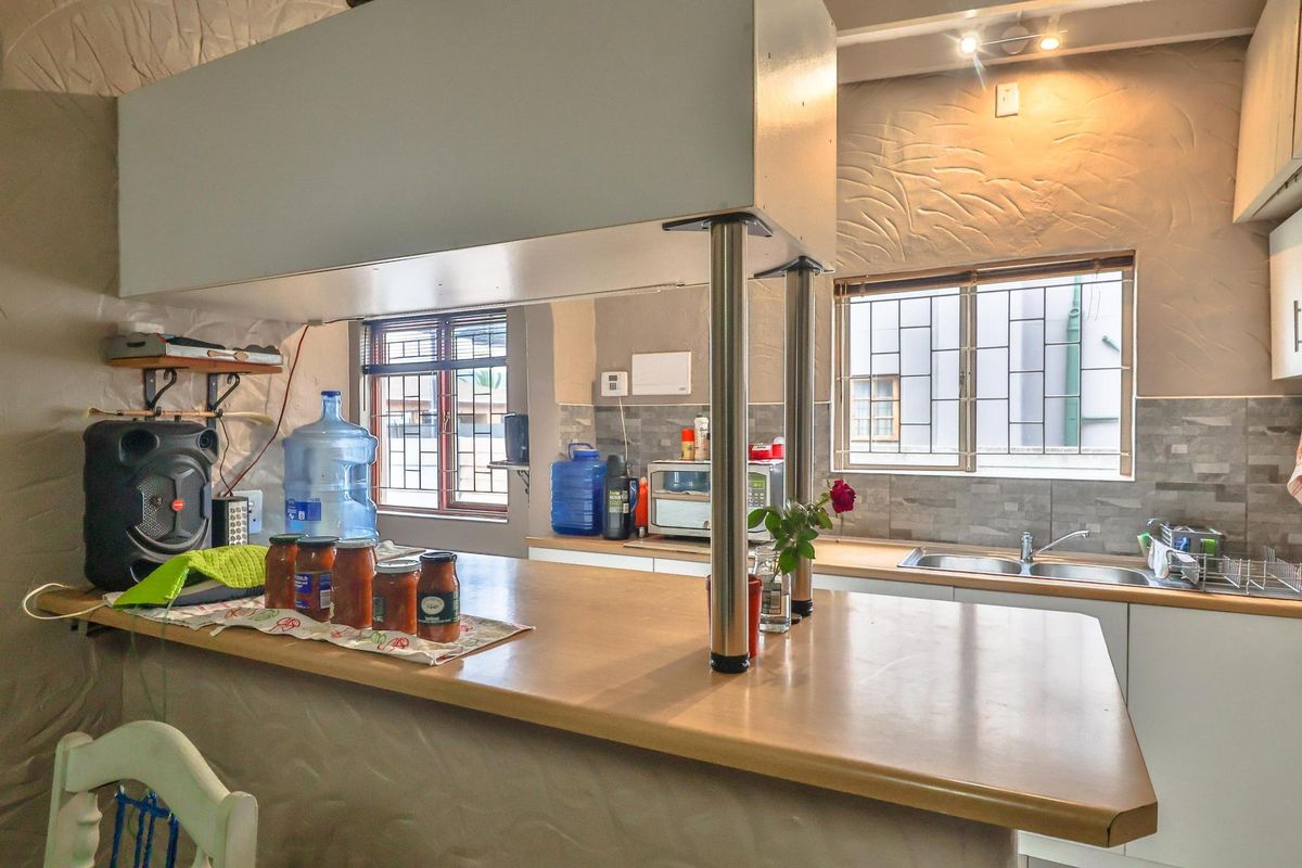 Functional kitchen featuring a breakfast bar, double basin sink, tiled splashback, and built-in cabinetry with ample counter space.