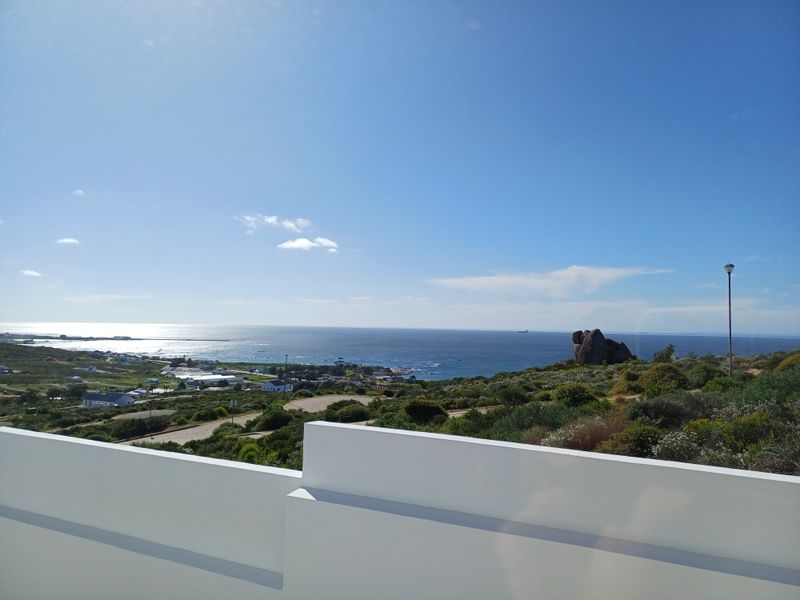 A scenic coastal view overlooking the ocean and surrounding landscape, captured from an elevated position with a white balustrade in the foreground.