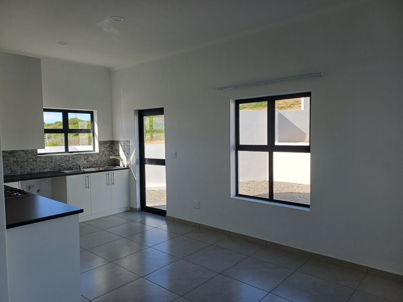 Modern open-plan kitchen and living area featuring tiled floors, built-in cabinetry, and large windows providing ample natural light.