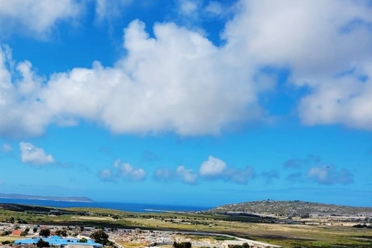 An elevated aerial view overlooking a residential neighborhood with distant coastal and landscape scenery.