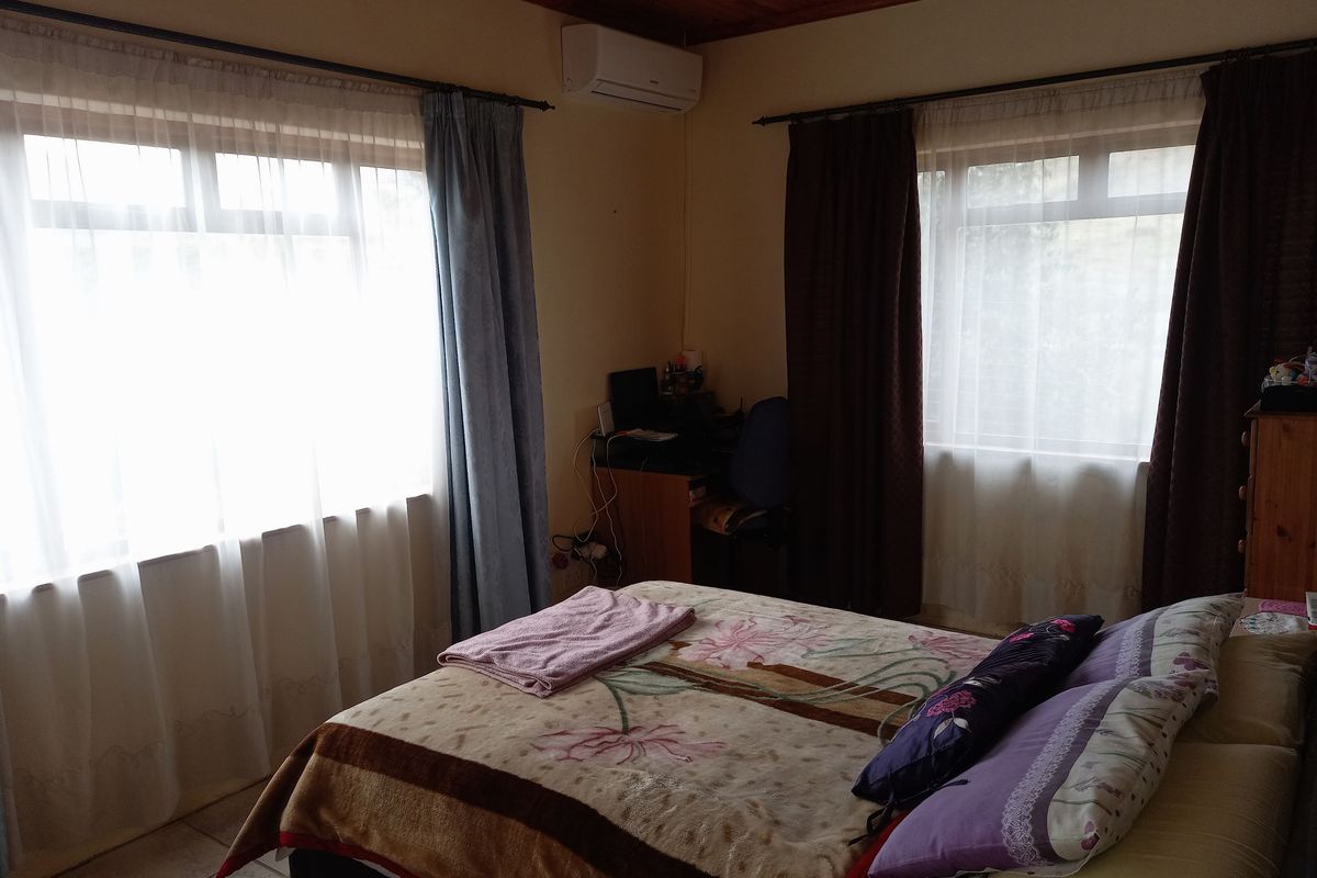 A bedroom featuring a timber-clad ceiling, tiled flooring, and a wall-mounted air conditioning unit.