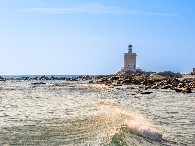 A scenic coastal view featuring a lighthouse situated on a rocky shoreline overlooking the ocean.
