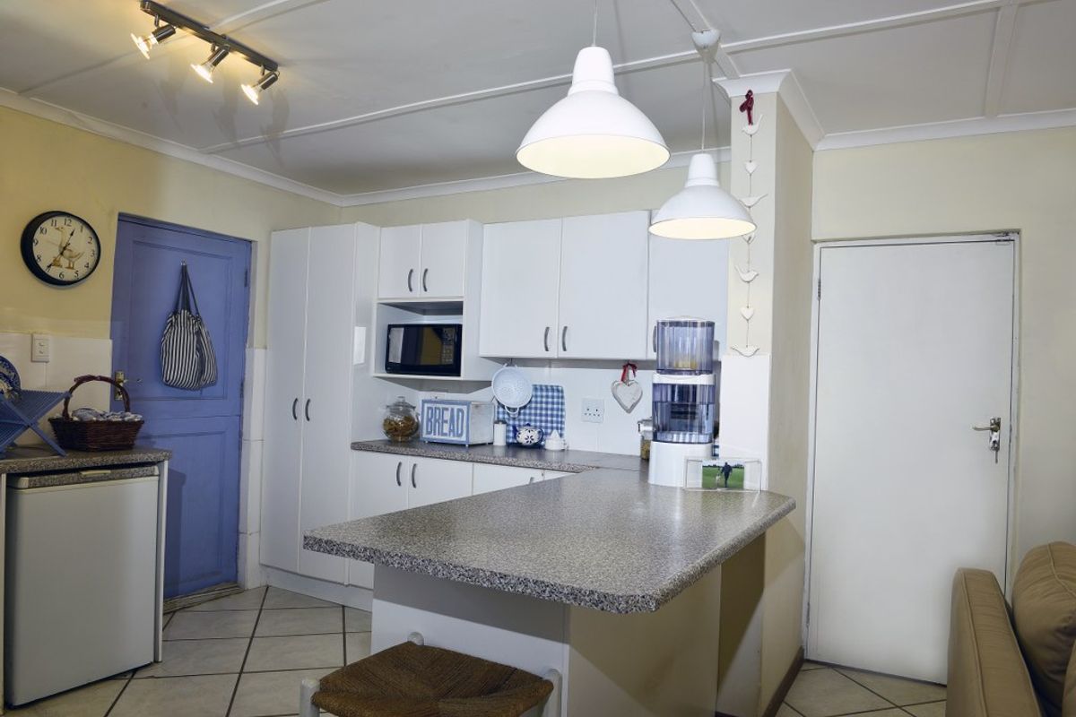 A functional kitchen featuring white cabinetry, laminate countertops, a breakfast bar, and tiled flooring, providing a practical and compact cooking and preparation space.