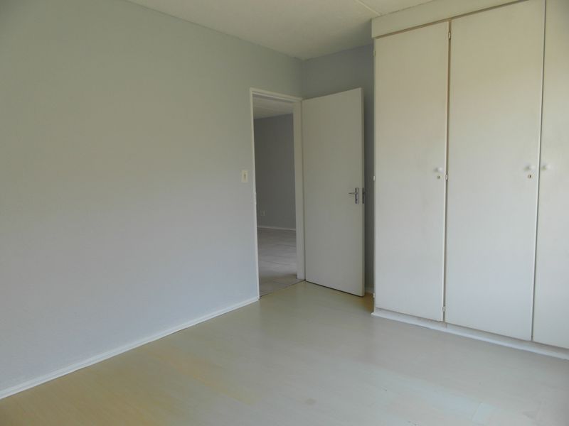 A clean, empty bedroom featuring neutral walls, light-toned flooring, and built-in storage cupboards.