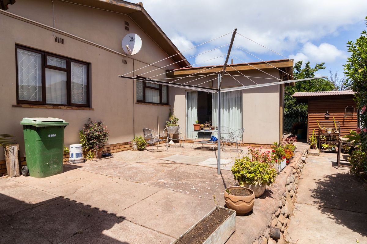Rear exterior view featuring a paved patio area, sliding glass door access, and a built-in rotary clothesline.