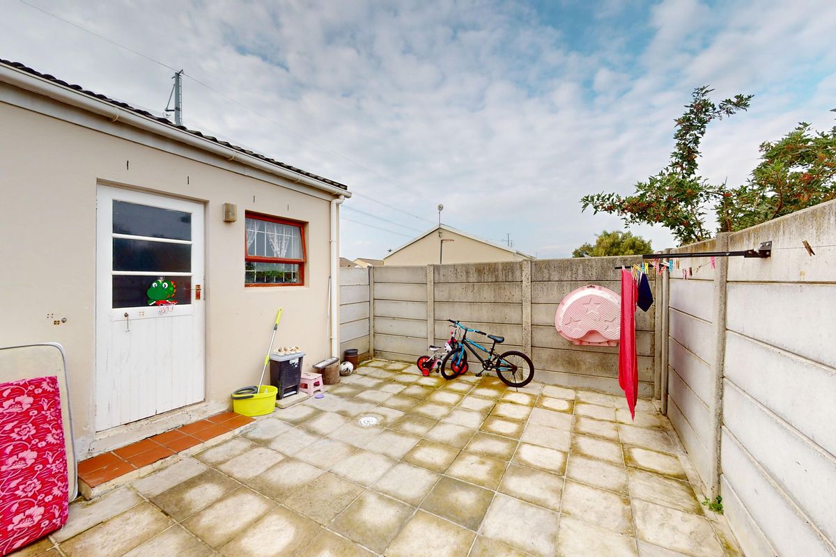 A private rear courtyard featuring paved flooring and high boundary walls, providing a functional outdoor space accessible from the main dwelling.