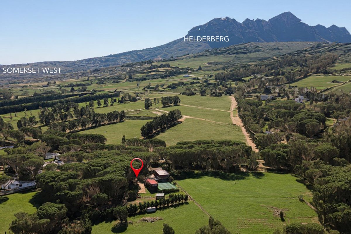 Aerial view of a small holding property situated in a rural landscape with prominent mountain views.