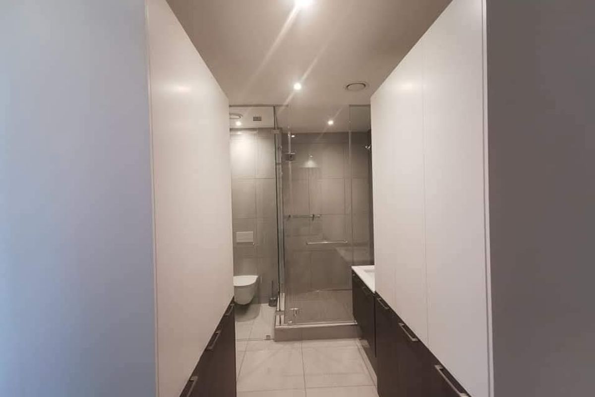Modern bathroom featuring a glass-enclosed shower, wall-mounted toilet, and sleek built-in cabinetry with integrated storage.