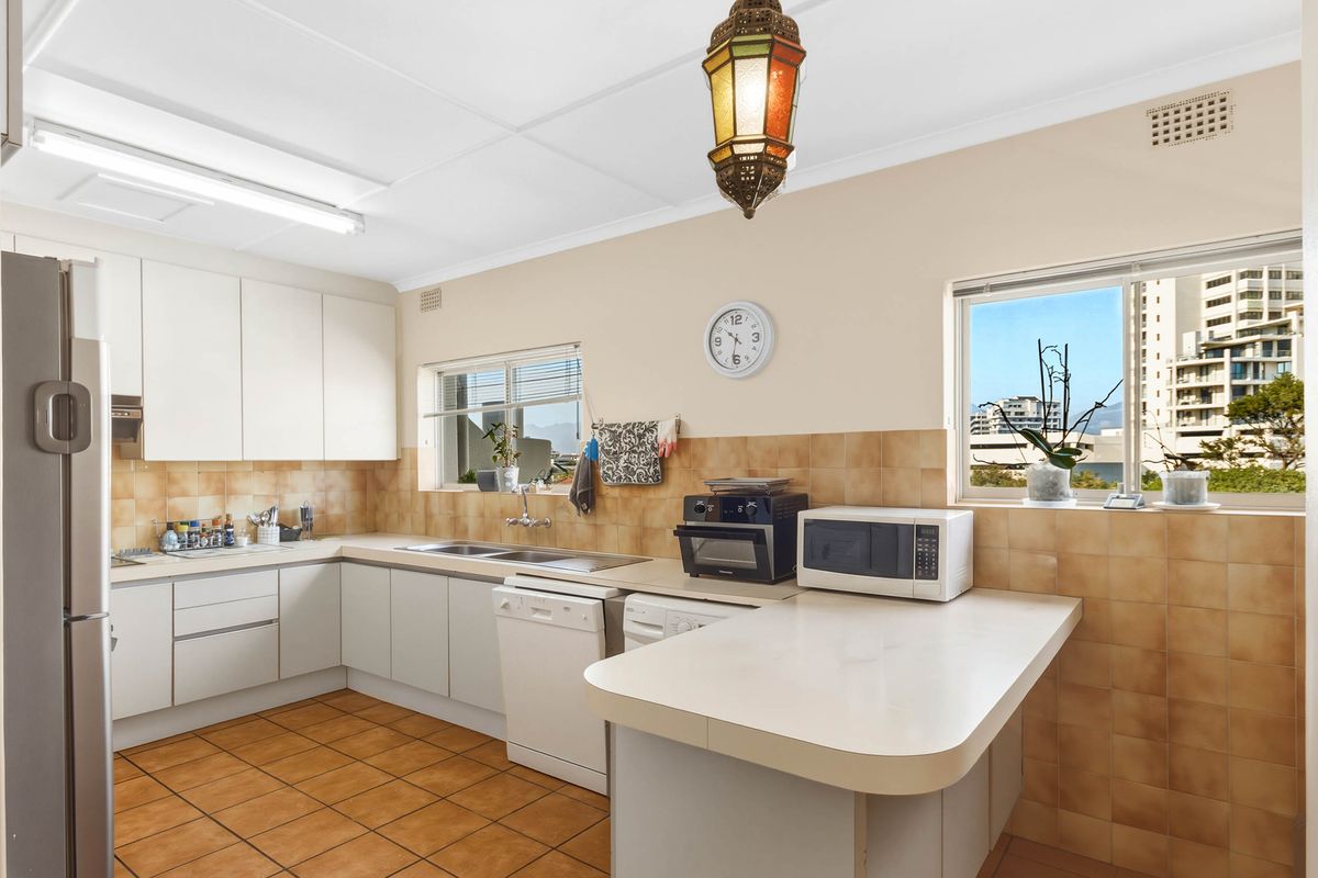 A functional kitchen featuring laminate countertops, ceramic tile backsplash, double basin sink, and built-in cabinetry with integrated dishwasher and extractor fan.