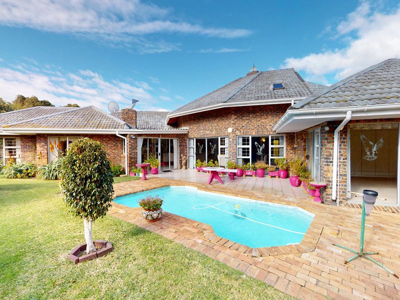 A spacious rear garden featuring a swimming pool, brick-paved patio area, and face brick exterior with multiple sliding door access points.