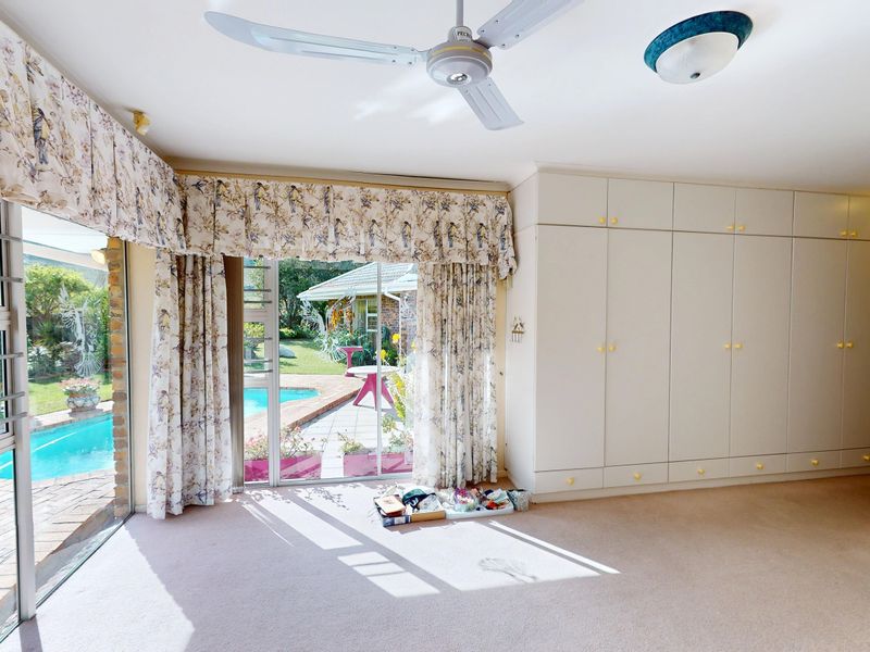 Spacious bedroom featuring extensive built-in cabinetry, a ceiling fan, and large sliding glass doors providing direct access to the pool area.