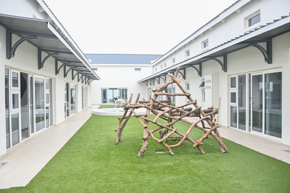 A well-maintained rear courtyard featuring an artificial lawn, tiled walkways, and multiple sliding glass door access points to the surrounding building wings.