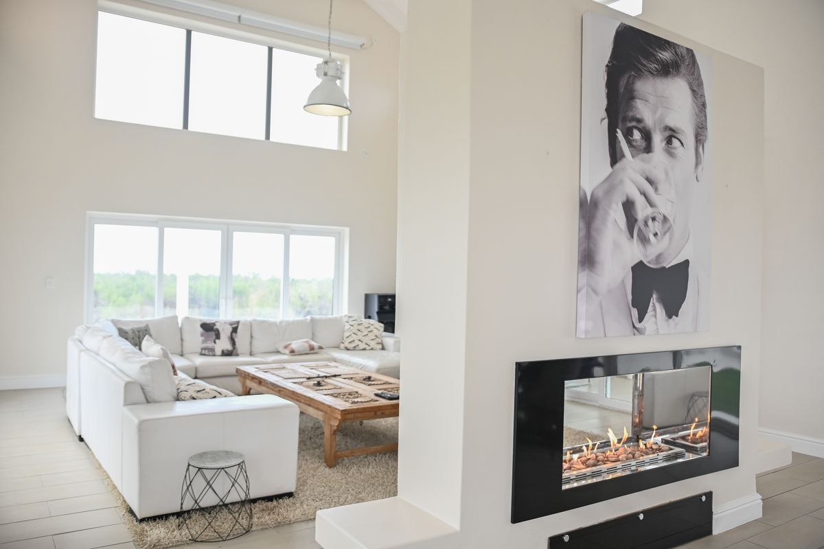 Spacious living room featuring a modern double-sided fireplace, vaulted ceilings, and large windows that provide ample natural light.