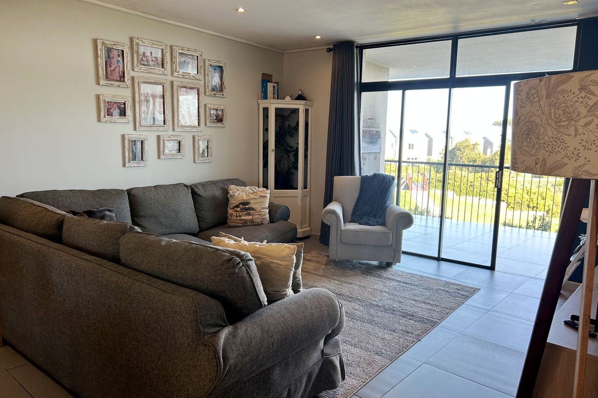 A bright living room featuring tiled flooring and large sliding glass doors that provide access to an outdoor balcony area.