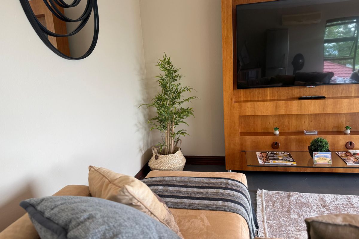 A cozy living room area featuring a large built-in wooden media unit and wall-mounted air conditioning.