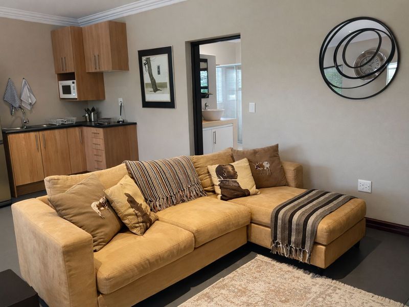 Open-plan living area featuring a compact kitchen with wood-finish cabinetry and laminate countertops, leading into a functional living space with neutral wall tones.
