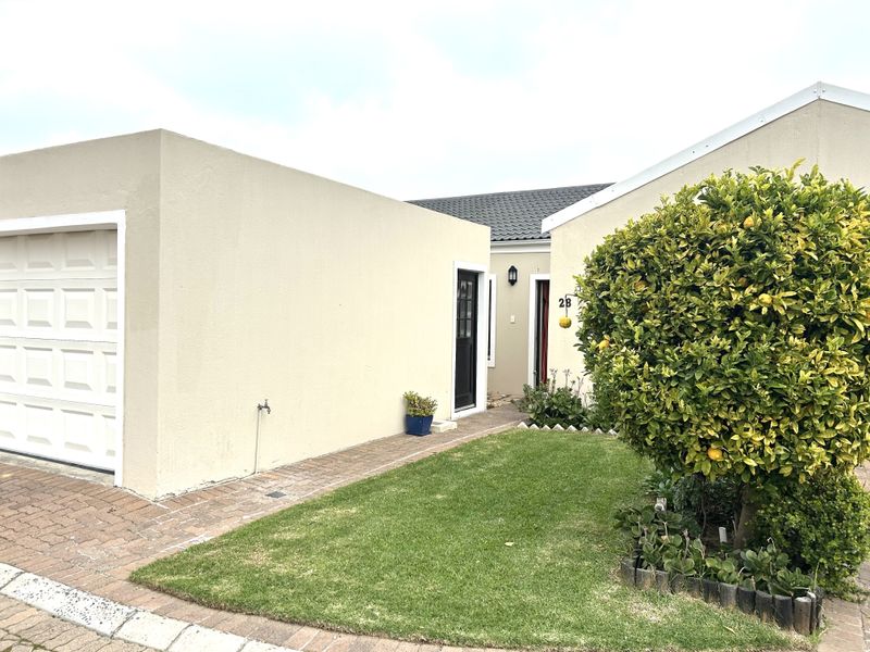 Front exterior view of the property featuring a paved driveway, single garage, and a well-maintained front garden area.