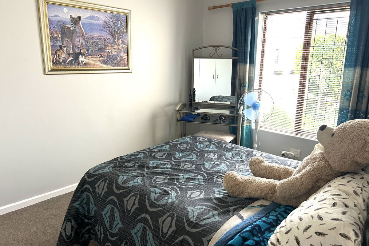 A standard bedroom featuring carpeted flooring, a window with fitted blinds, and a curtain rod.