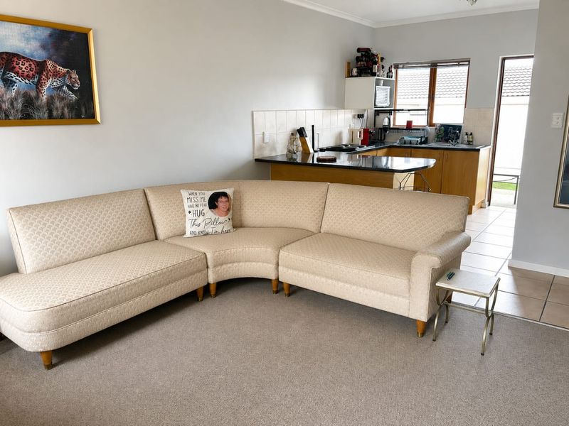Open-plan living area featuring a functional kitchen with granite countertops and tiled flooring, seamlessly connected to a carpeted lounge space.