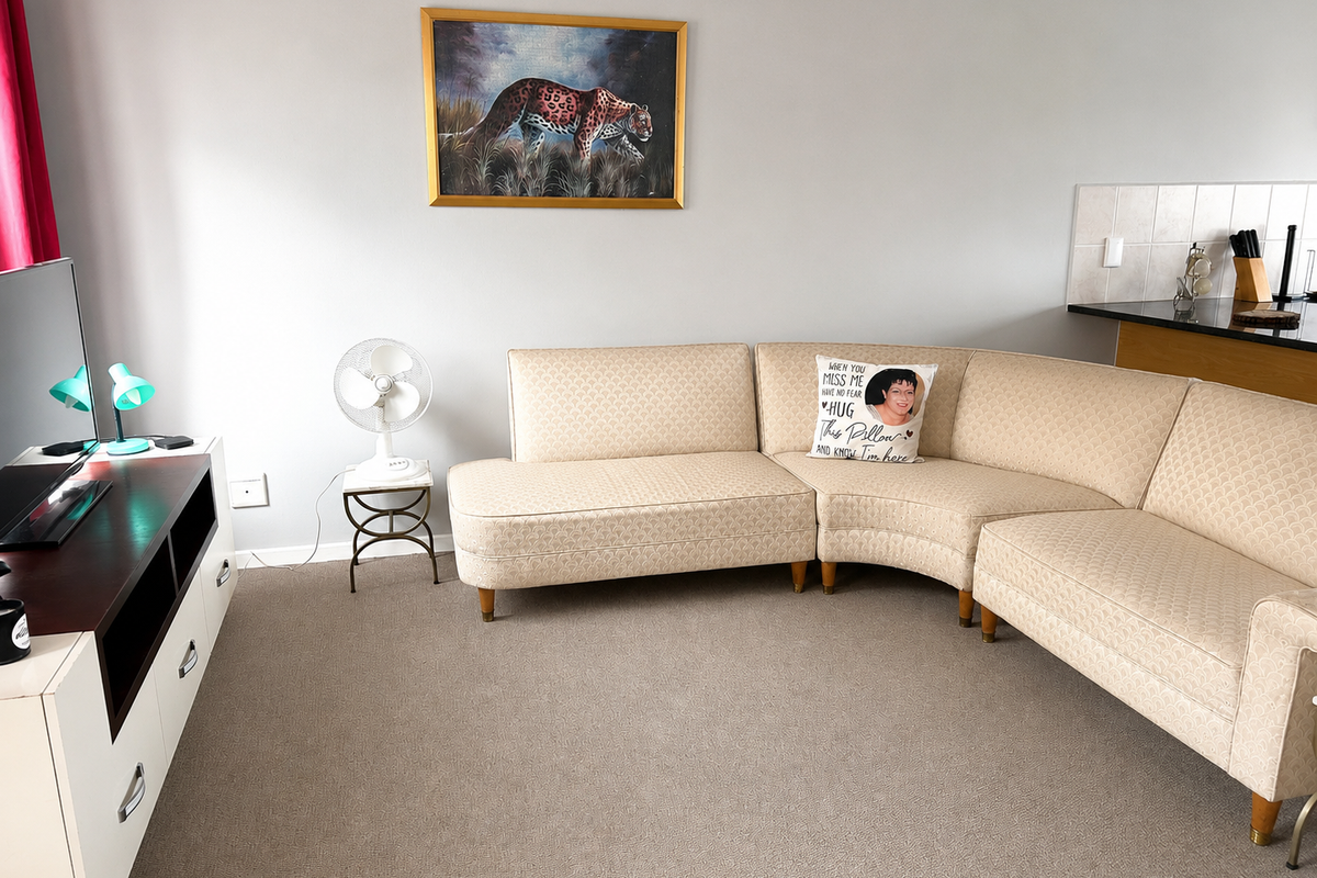 A comfortable living room area featuring neutral carpeting and an open-plan layout adjacent to the kitchen breakfast bar.