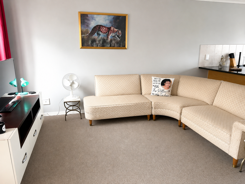 A comfortable living room area featuring neutral carpeting and an open-plan layout adjacent to the kitchen breakfast bar.