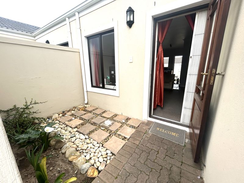 A small, low-maintenance rear courtyard featuring a paved patio area, pebble landscaping, and direct access to the interior living space.