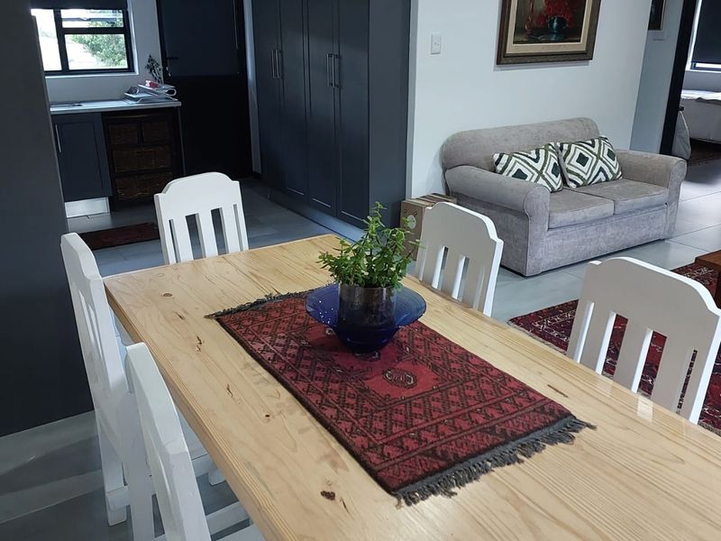 Open plan living and dining area featuring modern dark cabinetry, tiled flooring, and a functional kitchen workspace.