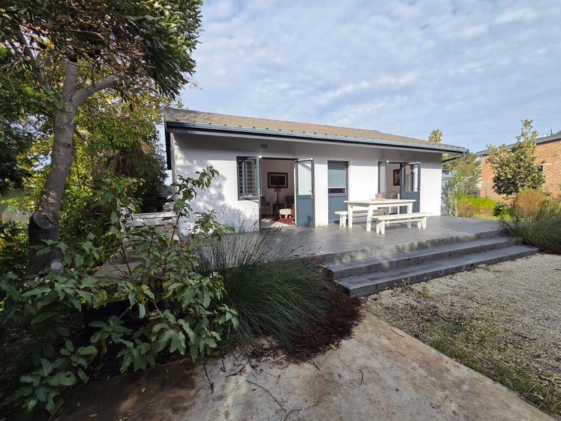 Rear view of the property featuring a tiled patio area with double door access and concrete steps leading to the garden.